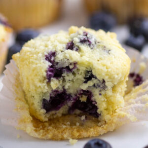 Blueberry muffin with a bite taken out and blueberries showing in the center.