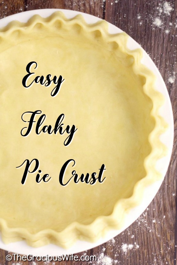 Pie crust rolled out and fluted in a white pie dish on a rustic wood background