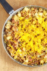 Farmer's Breakfast Skillet Recipe - an easy, hearty breakfast recipe idea with potatoes, ham, bacon, and veggies, topped with cheese and eggs. We love this recipe for brinner too!