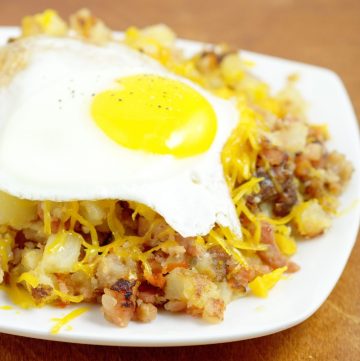 Farmer's Breakfast Skillet Recipe - an easy, hearty breakfast recipe idea with potatoes, ham, bacon, and veggies, topped with cheese and eggs. We love this recipe for brinner too!
