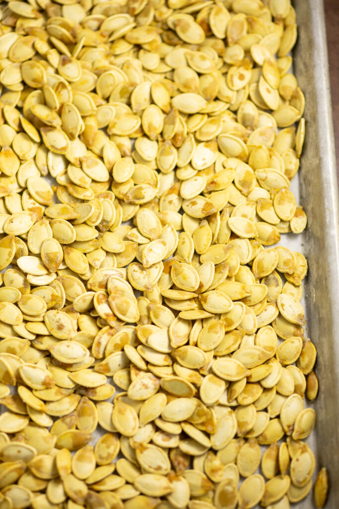 Overhead view of toasted pumpkin seeds on a metal baking sheet.