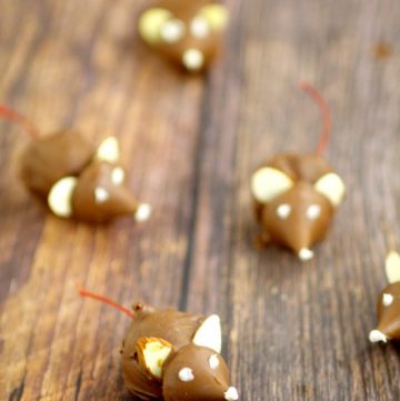 These fun Chocolate Cherry Christmas Mice made from chocolate covered cherries with almond slices and Kisses, are adorable Christmas candy treats recipe and a great addition to your dessert table. These will be so cute next to all the Christmas cookies!