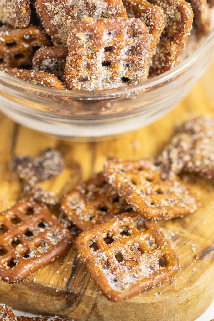 Cinnamon Sugar Pretzels on a wooden cutting board with a glass bowl of more pretzels behind.