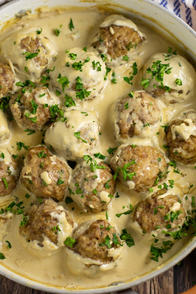 Swedish meatballs in a copper skillet with creamy brown gravy and fresh parsley on top.