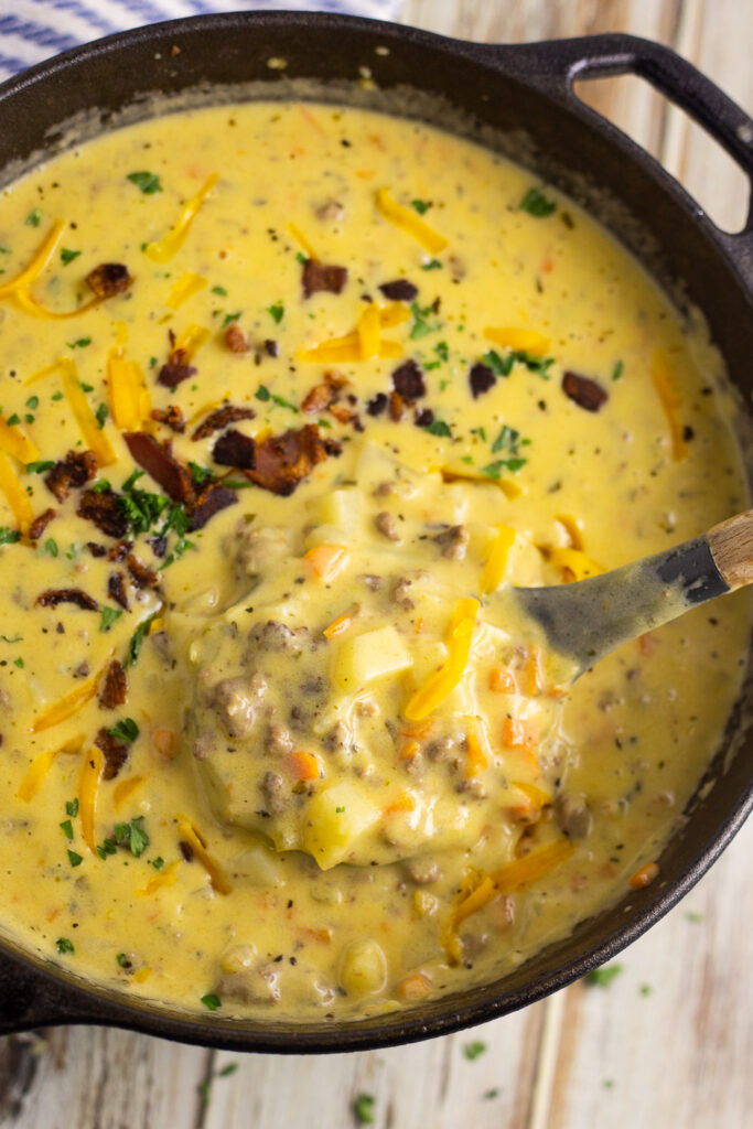 Dutch oven full of cheeseburger soup with a ladle taking out a scoop in the center