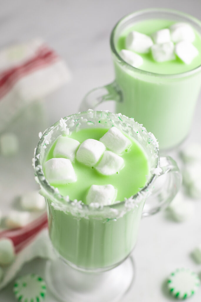 Overhead view of mint white hot chocolate dyed green, topped with mini marshmallows.