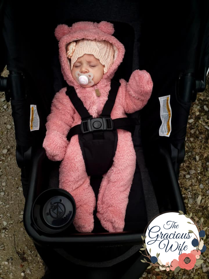 Baby in a stroller in a pink bear bunting sucking a MAM pacifier