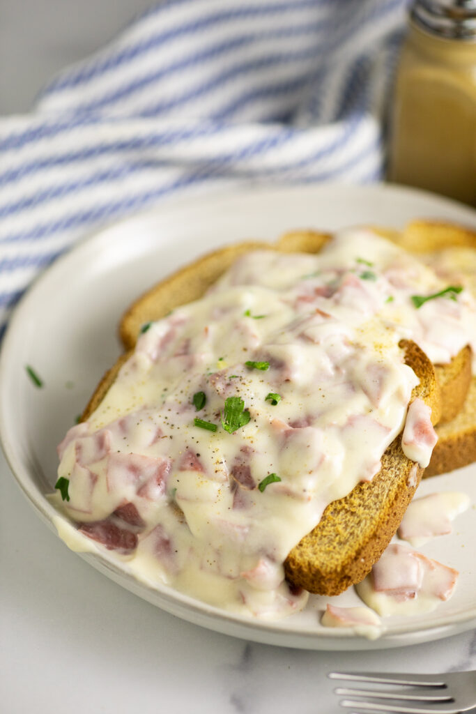 Creamed chipped beef over three pieces of toast topped with black pepper and freshly chopped parsley