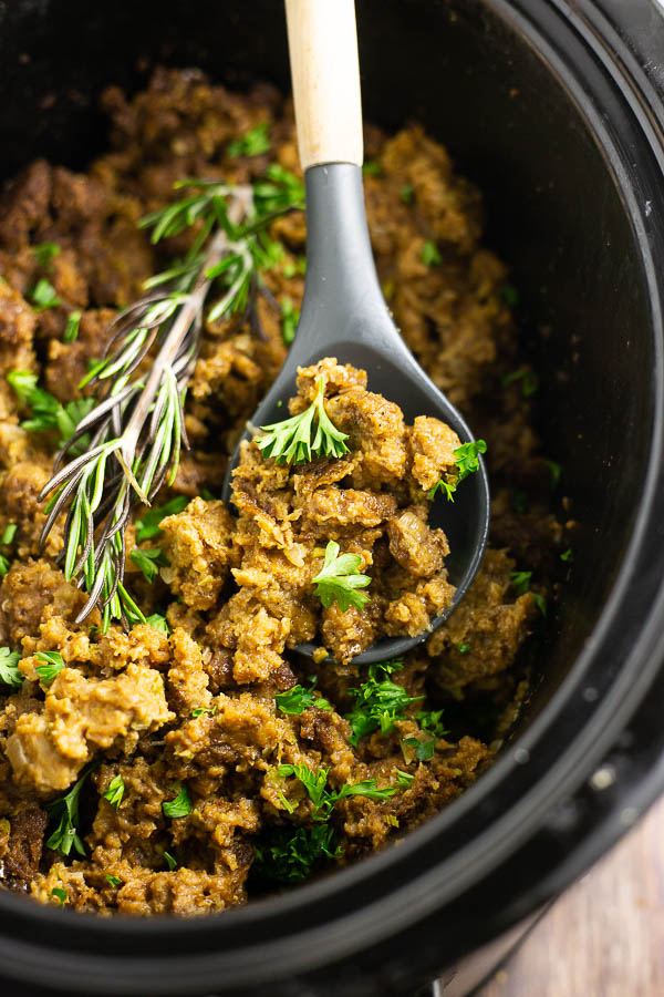 Wooden spoon in a black crock filled with stuffing and a rosemary sprig.