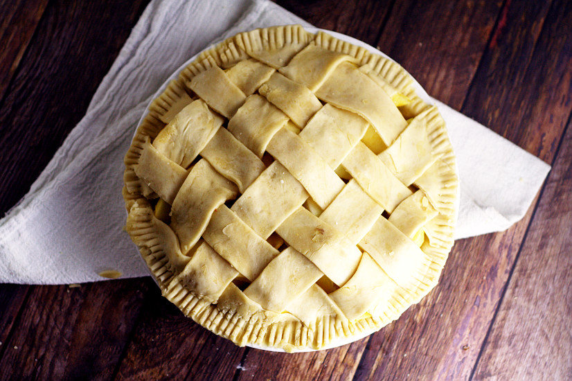 A finished lattice pie crust on a dark rustic wood background with a white linen.