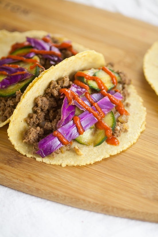 Asian Beef Tacos recipe with cucumber slaw - An Asian kick on your old family dinner favorite, these Asian Beef Tacos topped with cool sour cream, crisp cucumber slaw, and spicy Sriracha make taco night even more spectacular.  Wow, the slaw on these tacos really makes it amazing!