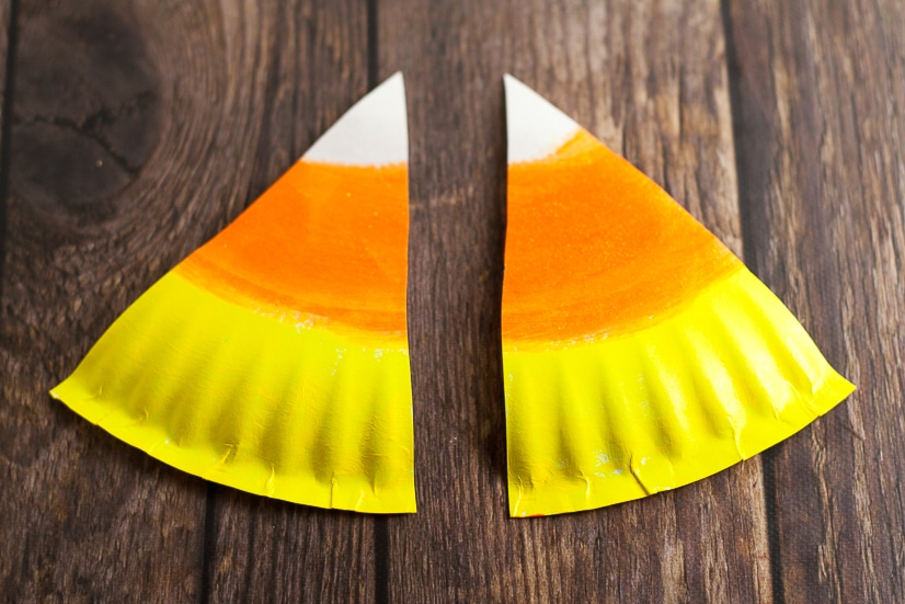 DIY Halloween Paper Plate Candy Corn Banner Tutorial - This cute and festive DIY Paper Plate Candy Corn Banner makes an adorable and cheap DIY Halloween decoration that's perfect for your home or even a Halloween party decoration.  So easy to make that even the kids could help!