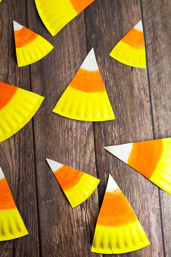 DIY Halloween Paper Plate Candy Corn Banner Tutorial - This cute and festive DIY Paper Plate Candy Corn Banner makes an adorable and cheap DIY Halloween decoration that's perfect for your home or even a Halloween party decoration.  So easy to make that even the kids could help!