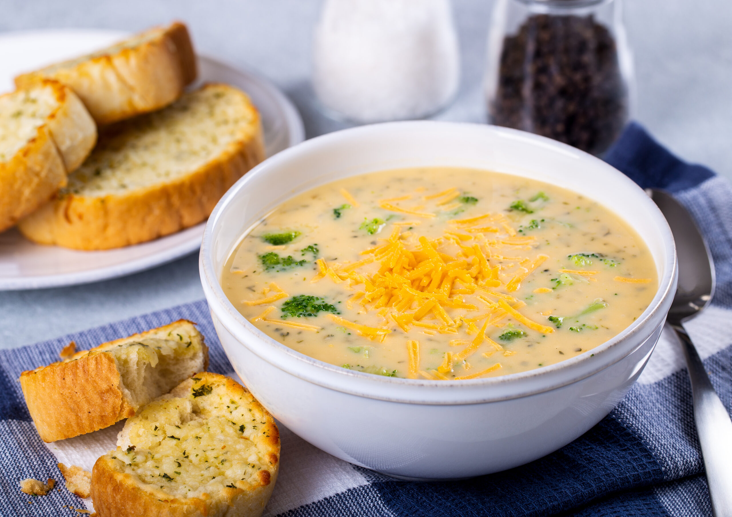 Crockpot broccoli cheese soup in a bowl next to crusty buttered bread