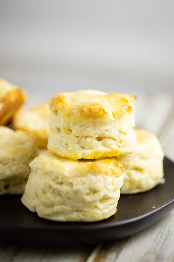 Biscuits stacked on a black matte plate on a white rustic wood background