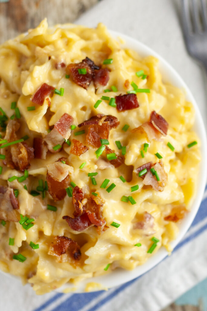 Overhead view of bacon cheddar bow tie pasta topped with crumbled bacon and fresh chives.`