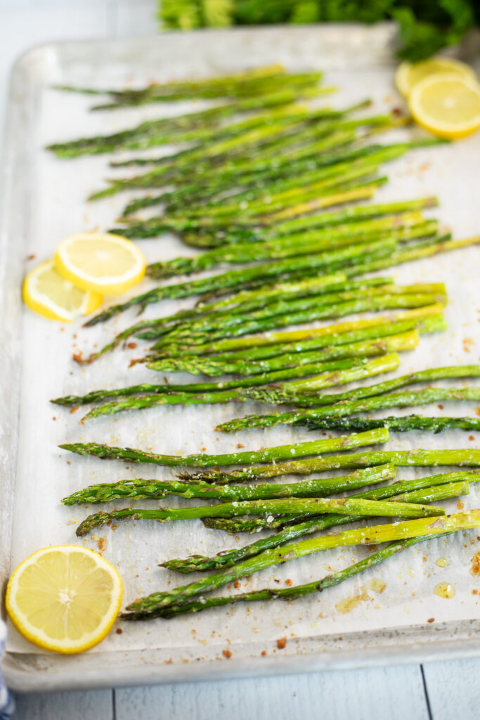 Oven roasted asparagus and lemon slices on a baking sheet lined with parchment paper.