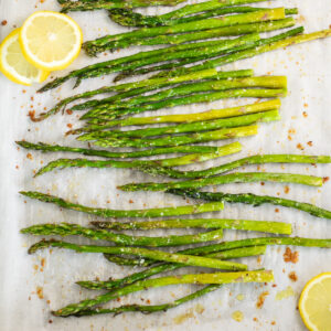 Oven roasted asparagus and lemon slices on a baking sheet lined with parchment paper.