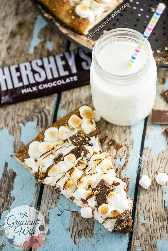 S'mores Pizza Recipe - S'mores Pizza with tons of gooey marshmallows and rich, decadent HERSHEY'S Milk Chocolate with a marshmallow cheesecake sauce, a chocolate drizzle, and a sprinkle of graham crackers, all on top of a cinnamon-sugar crust. This is such a quick and easy dessert recipe and it is soooo good. My kids love it. And I probably love it even more.  Who doesn't love s'mores?