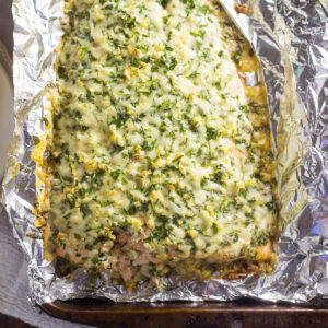 Overhead view of parmesan garlic herb salmon on foil on a baking sheet.
