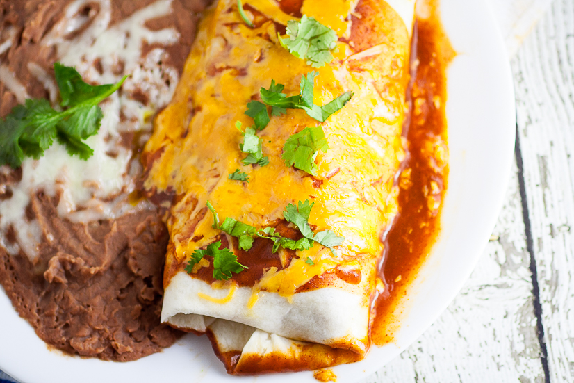 Rice and Black Bean Burritos Recipe - Quick and easy Mexican-inspired dinner recipe, these Rice and Black Bean Burritos are filled with flavorful rice and beans and smothered in enchilada sauce and cheese for a yummy vegetarian dinner perfect for Meatless Monday.