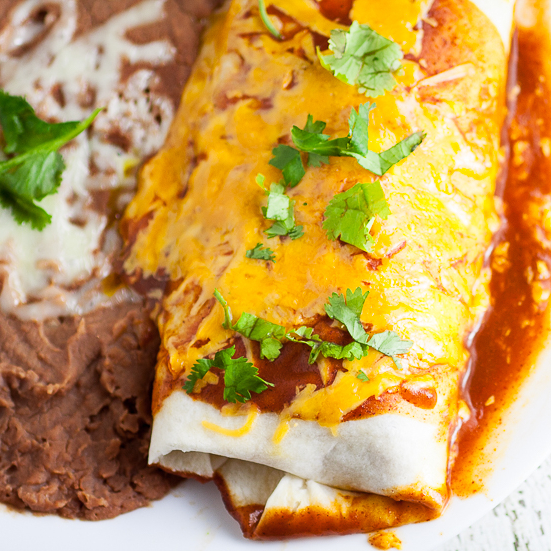 Rice and Black Bean Burritos Recipe - Quick and easy Mexican-inspired dinner recipe, these Rice and Black Bean Burritos are filled with flavorful rice and beans and smothered in enchilada sauce and cheese for a yummy vegetarian dinner perfect for Meatless Monday.