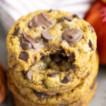 Overhead view of a stack of pumpkin chocolate chip cookies with a bite taken out of the top one.