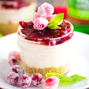Cranberry White Chocolate Cheesecake Recipe - rich white chocolate no bake cheesecake filling with just 3 ingredients topped with tangy cranberry sauce in a graham cracker crust. Make it a big cheesecake or make mini cheesecakes in jars.ย