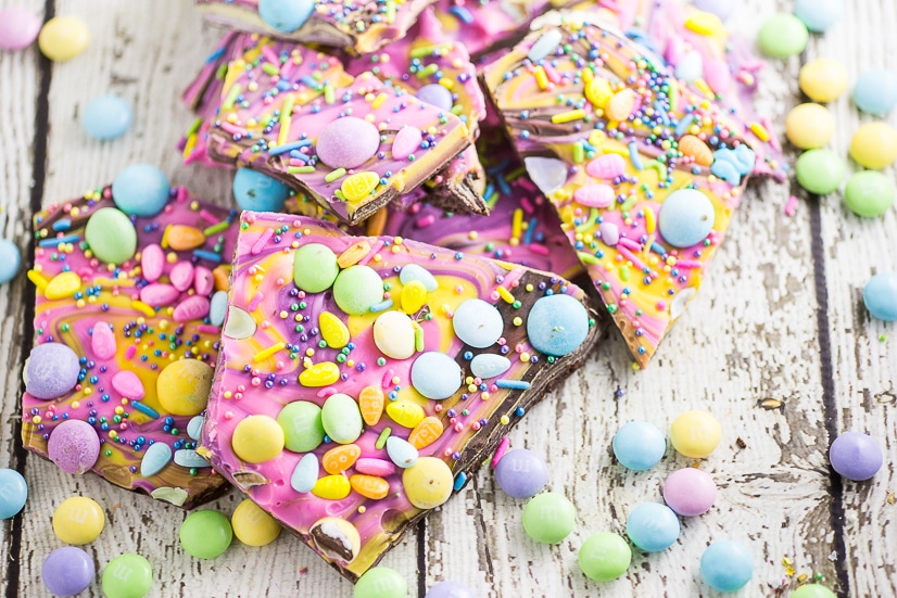 Chocolate Easter Bark with pastel Easter candies on a white wood background