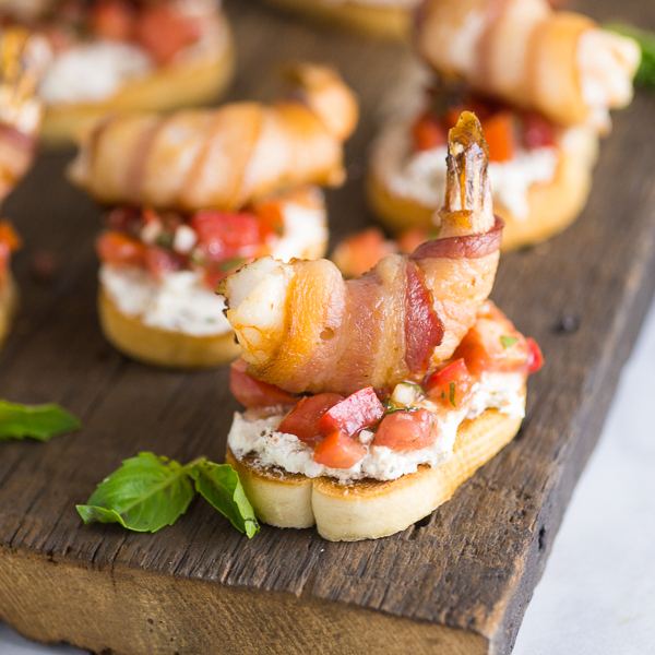 Creamy Bacon Shrimp Bruschetta recipe - Perfect appetizers for entertaining! This Creamy Bacon Shrimp Bruschetta recipe has it all with toasted baguette, a creamy garlic herb and bacon spread, balsamic vinaigrette, and THE BEST fresh basil and tomato bruschetta. Topped with a succulent bacon-wrapped shrimp! Make it for all your summer parties!