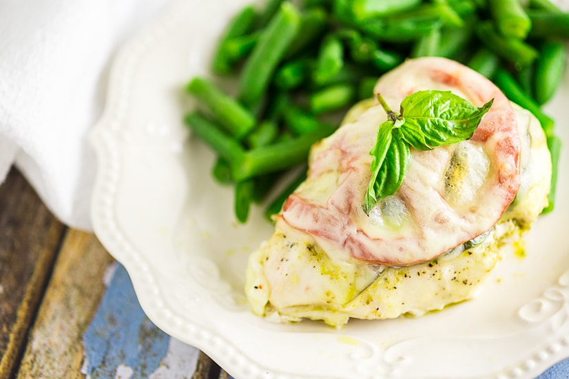 Quick and easy Baked Caprese Chicken features cheesy chicken breast with basil pesto, basil leaves, and a slice of fresh tomato for a fresh and healthy weeknight dinner! 
