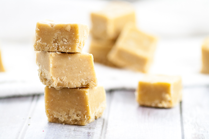 3 pieces of peanut butter fudge stacked on a gray weathered wood background