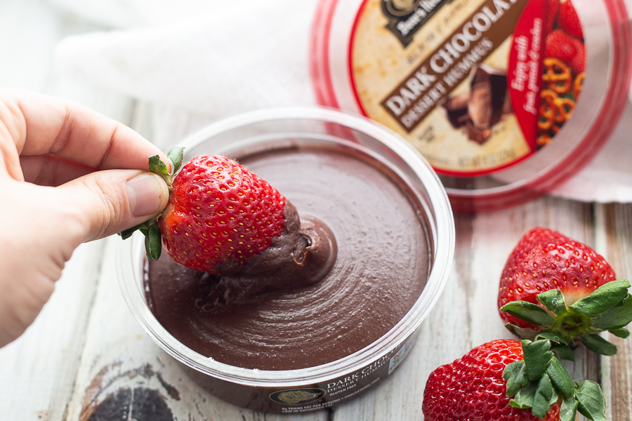 Strawberry being dipped into dark chocolate hummus