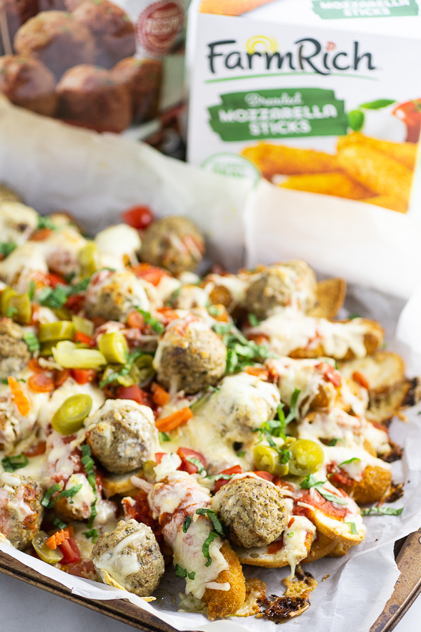 Baked Italian Nachos on parchment paper on a baking sheet with Farm Rich mozzarella sticks package in the background