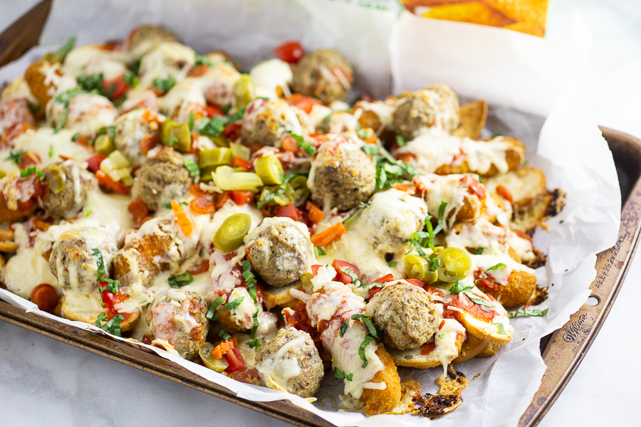 Baked Italian Nachos are the ultimate snack and party appetizer with baguette crisps loaded down with pizza sauce, mozzarella sticks, meatballs, pepperoni, and lots of gooey cheese. 