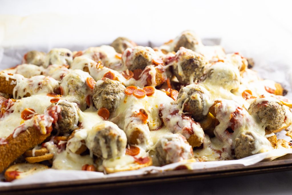 Baked Italian nachos on a baking sheet with white background after they have been baked