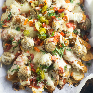 Baked Italian Nachos are the ultimate snack and party appetizer with baguette crisps loaded down with pizza sauce, mozzarella sticks, meatballs, pepperoni, and lots of gooey cheese.
