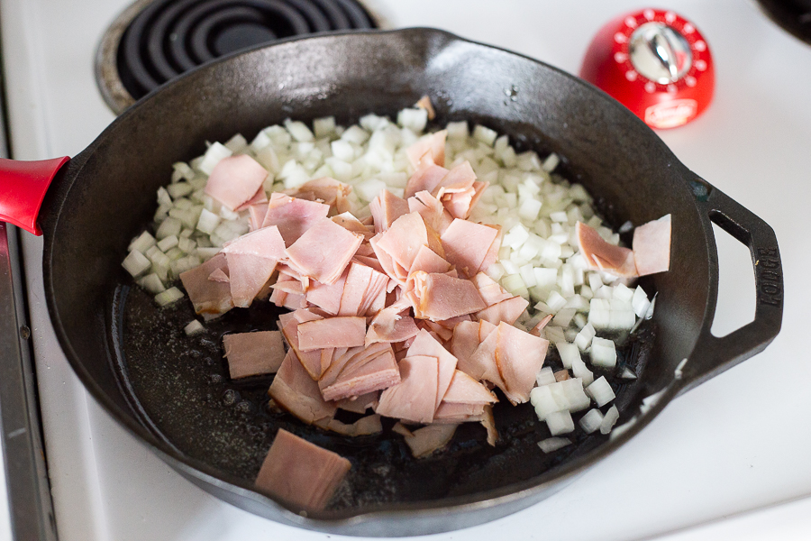 Ham and onions in a cast iron skillet sauteeing with butter