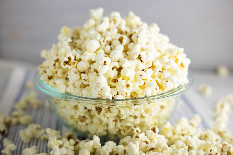 Popcorn in a clear class bowl on a white and blue striped placemat
