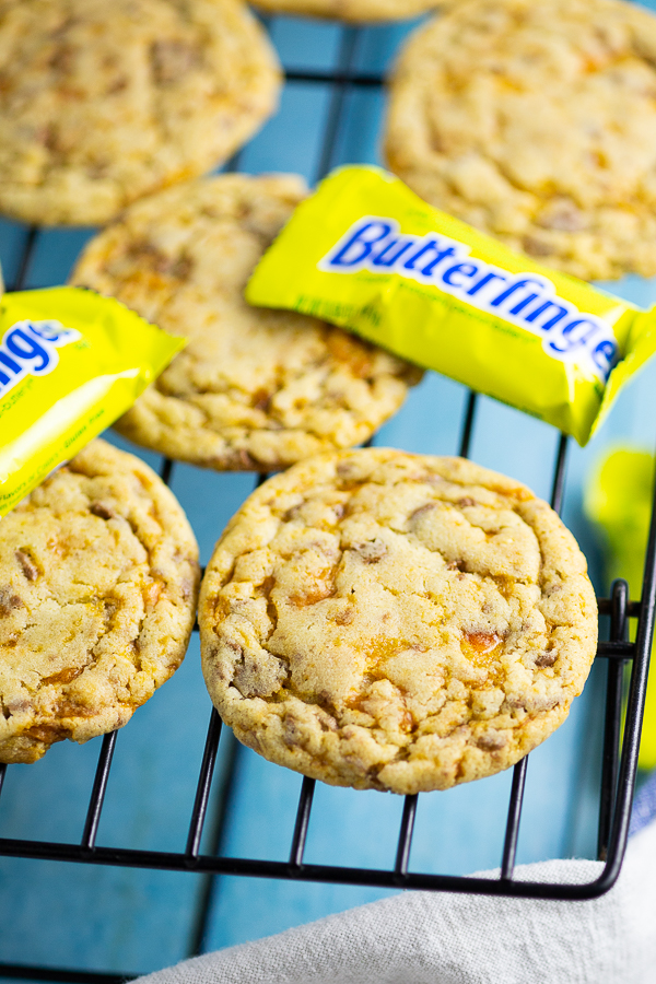 Butterfinger Cookies on a cooling rack with mini Butterfingers with an aqua wood background