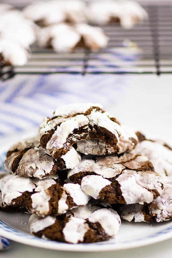 Chocolate crinkle cookies on a white plate with a cooling rack in the background