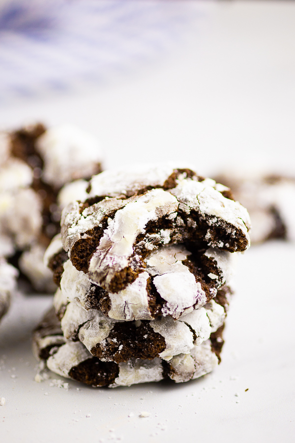 Four chocolate crinkle cookies stacked with the top one with a bite out of it
