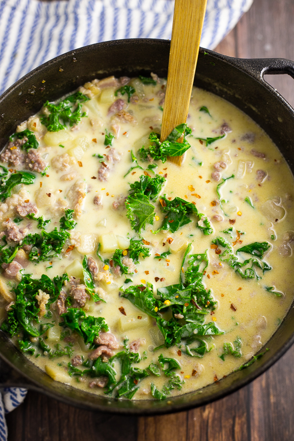 Large Dutch oven full of Zuppa Toscana with a wooden spoon in the middle