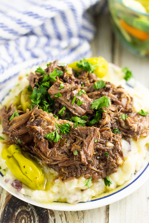 Mississippi mud roast on top of mashed potatoes on a white plate on a rustic wood background