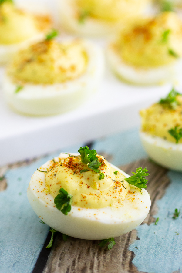 Deviled egg on a rustic wood background with more eggs behind it