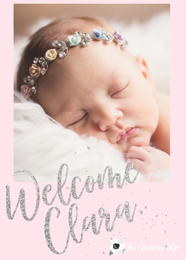 Picture of a baby with rainbow flower headband laying on a white fuzzy blanket. Picture is on a light pink background with the text "Welcome Clara."