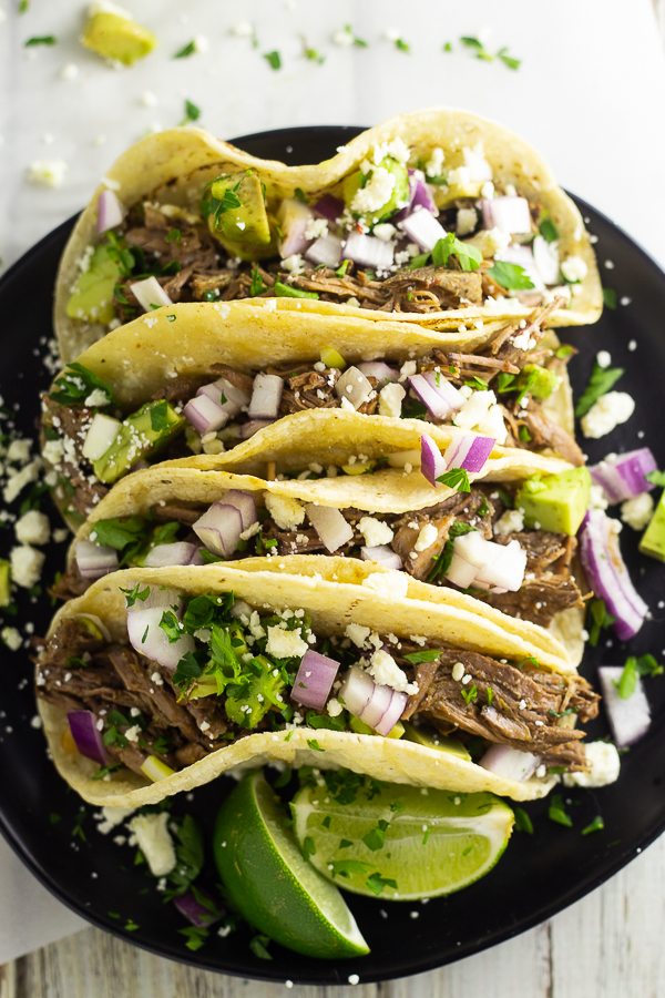 4 street tacos on a black plate stuffed with Chipotle barbacoa, cilantro, redo onion, and queso fresco.