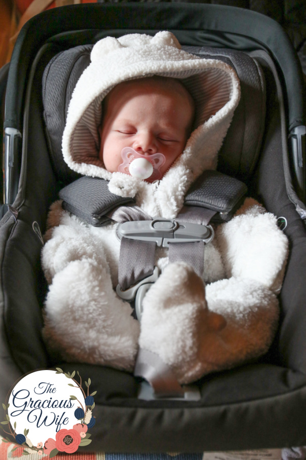Newborn baby wearing a fuzzy bear bunting in a car seat