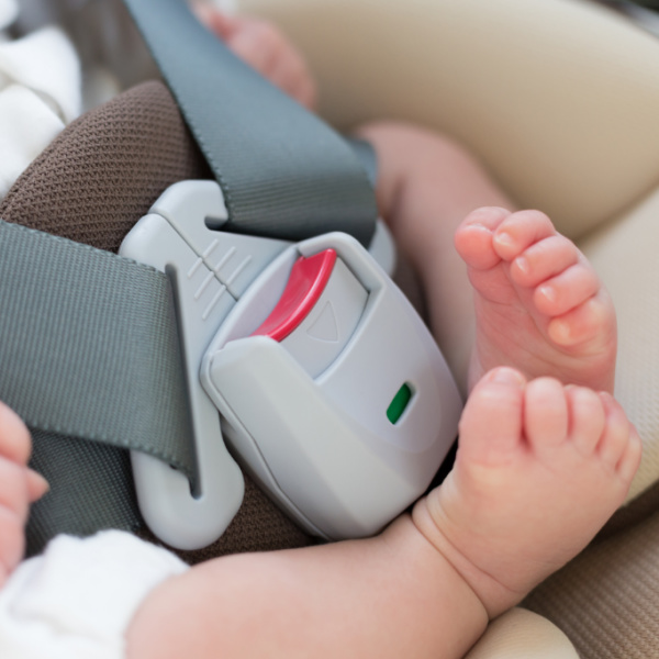 Baby feet next to a car seat buckle