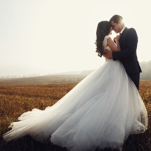 Man and woman couple embracing outdoors wearing a wedding dress and a suit